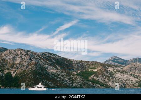 Le yacht blanc de luxe navigue sur la baie de Kotor au Monténégro, sur le fond des montagnes, ciel bleu avec des nuages. Banque D'Images