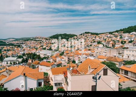 Toits orange de vieilles maisons à Sibenik sur fond de ciel bleu et de verdure Banque D'Images