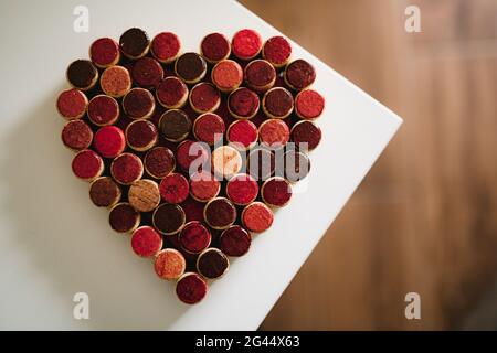 Les bouchons de bouteilles de vin sont alignés en forme de coeur sur un fond blanc. Banque D'Images