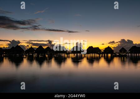 Bungalows sur l'eau du Sofitel IA ora Beach Resort dans le lagon de Moorea à l'aube, Moorea, les îles du vent, la Polynésie française, le Pacifique Sud Banque D'Images