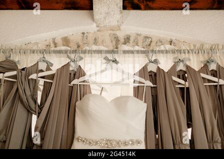 Gros plan de la robe de mariage de la mariée sur le fond des robes de demoiselle d'honneur sur la corniche. Banque D'Images