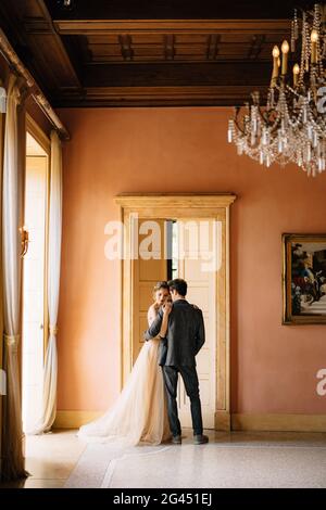 Le marié encadre la mariée contre le fond de la porte haute à la chambre de la vieille villa. Lac de Côme Banque D'Images