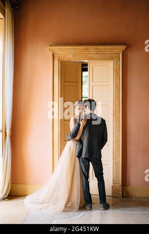 Le marié encadre la mariée contre le fond de la porte haute à la chambre de la vieille villa. Lac de Côme. Gros plan Banque D'Images