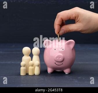 Figurines de famille en bois et banc de porc en céramique rose sur fond bleu Banque D'Images