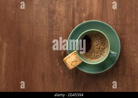 Une tasse de café noir avec un biscuit, tiré d'en haut sur un fond rustique foncé en bois Banque D'Images