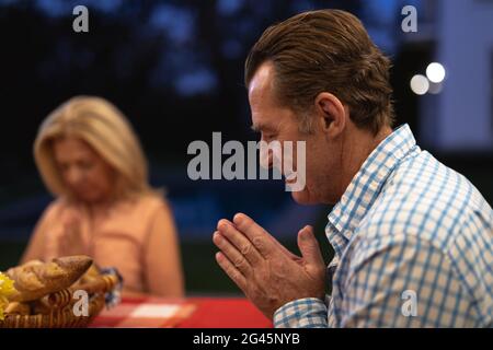 Famille Caucasienne de plusieurs générations priant avant de manger Banque D'Images