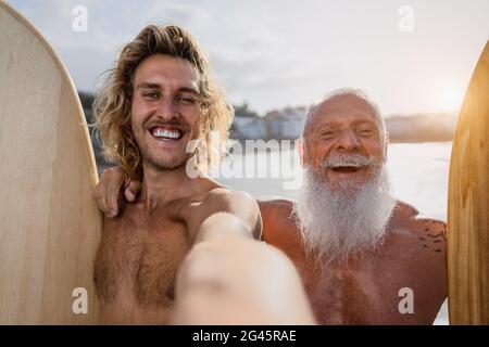 Des surfeurs heureux qui prennent le selfie tout en surfant ensemble au coucher du soleil - concept de style de vie et d'amitié sport extrême Banque D'Images