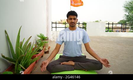 Homme indien serein pratiquant le yoga à l'extérieur. Jeune praticien de yoga s'entraîner et s'asseoir dans lotus poser avec les yeux fermés. Yoga et méditation concep Banque D'Images