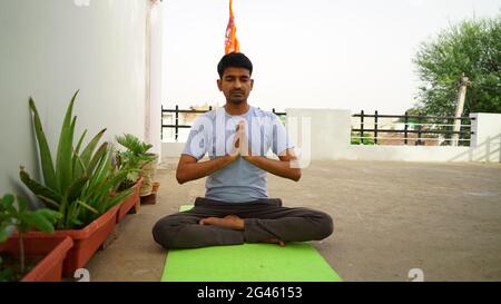 Homme indien serein pratiquant le yoga à l'extérieur. Jeune praticien de yoga s'entraîner et s'asseoir dans lotus poser avec les yeux fermés. Yoga et méditation concep Banque D'Images