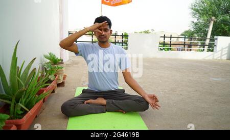 Homme indien serein pratiquant le yoga à l'extérieur. Jeune praticien de yoga s'entraîner et s'asseoir dans lotus poser avec les yeux fermés. Yoga et méditation concep Banque D'Images