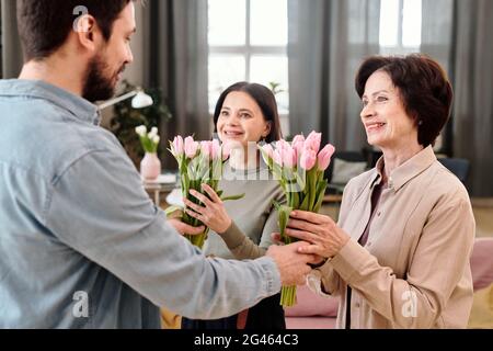 Des femelles gaies avec des tulipes regardant un jeune homme gentil Banque D'Images