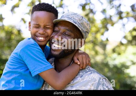 Homme afro-américain portant un uniforme militaire tenant son fils Banque D'Images