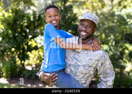 Homme afro-américain portant un uniforme militaire tenant son fils Banque D'Images