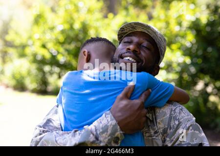 Homme afro-américain portant un uniforme militaire tenant son fils Banque D'Images