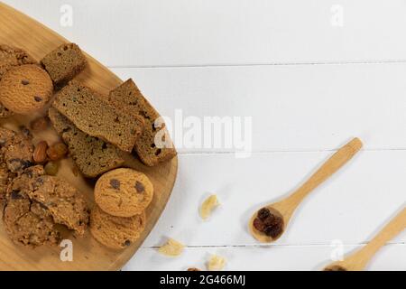 Vue des cookies placés sur une planche à découper en bois surface en bois et cuillères avec fruits secs Banque D'Images
