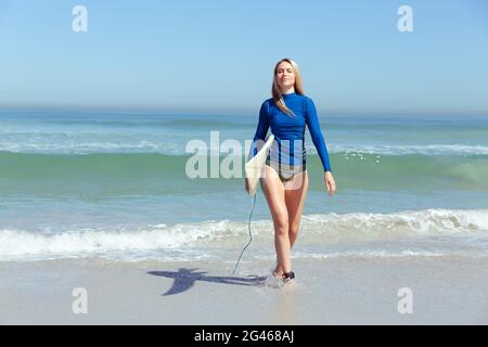 Femme caucasienne pendant la session de surf à la plage Banque D'Images