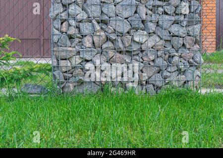 Une clôture de grillage métallique gabion de pierres naturelles et les montants de support. Banque D'Images