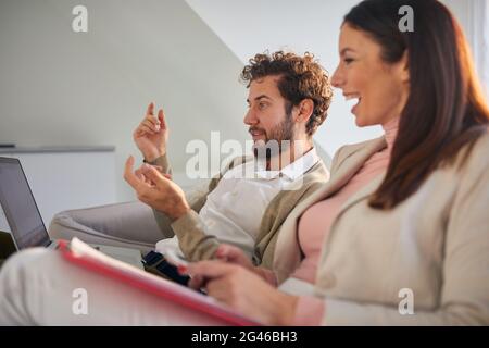 Un couple d'affaires joyeux qui a un bon moment sur le canapé à loisir dans une atmosphère détendue dans un appartement. Affaires, couple, loisirs, ensemble Banque D'Images