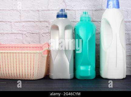 Les bouteilles de détergent liquide et les paniers à linge en plastique sont vides sur une table bleue en bois Banque D'Images