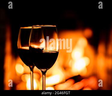 Deux verres de vin rouge sur le fond des lumières de cheminée Banque D'Images