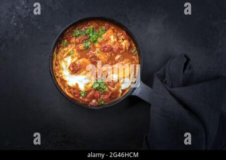 Le traditionnel plat national israélien shakshouka est servi pour le petit-déjeuner avec des œufs pochés dans une sauce tomate et des abats de piment et d'oignons Banque D'Images