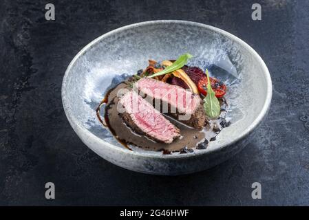 Tagliata di manzo italien de style moderne avec bifteck de sirloin en tranches d'âge sec et légumes à la sauce aux truffes servis à proximité Banque D'Images