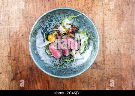 Tagliata di manzo italien de style moderne avec bifteck de sirloin en tranches d'âge sec et salade d'agneau servi comme vue de dessus dans une céramique design Banque D'Images