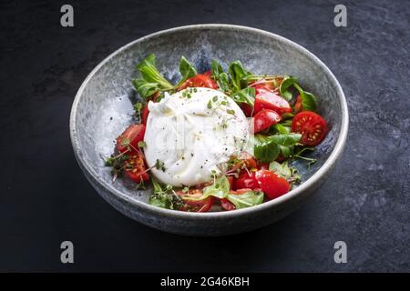 Le fromage au lait de vache italien Apulia Burrata de style moderne à base de mozzarella et de crème servi avec une salade de tomates et de maïs en céramique Banque D'Images