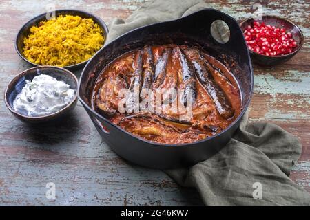 Le ragoût d'aubergines d'agneau persan lentement cuisiné de style moderne khoresh bademjan servi avec du riz et du yaourt dans un pot design Banque D'Images