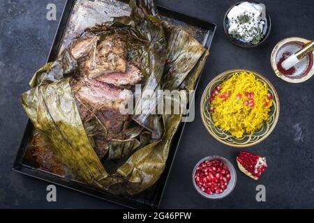 Le shuwa d'agneau omanais cuit lentement, enrobé d'épices et enveloppé de feuilles de banane, servi avec du riz et du yaourt comme vue de dessus sur un Banque D'Images