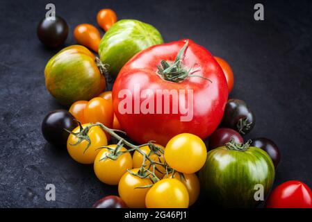 Collection traditionnelle de tomates fraîches italiennes proposée en gros plan sur un tableau noir rustique Banque D'Images