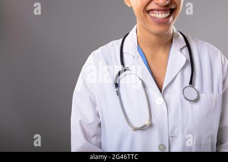 Section moyenne d'afro-américaine femme médecin souriant contre le gris arrière-plan Banque D'Images