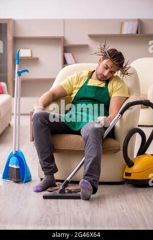 Jeune entrepreneur homme portant une couronne à pickly sur la tête faisant des travaux ménagers Banque D'Images