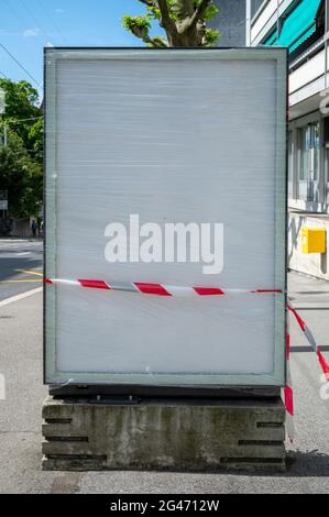 Panneau publicitaire vierge endommagé avec ruban rouge et blanc sur la rue. Verre cassé. Notion de violence et de vandalisme. Lausanne, Suisse. Banque D'Images