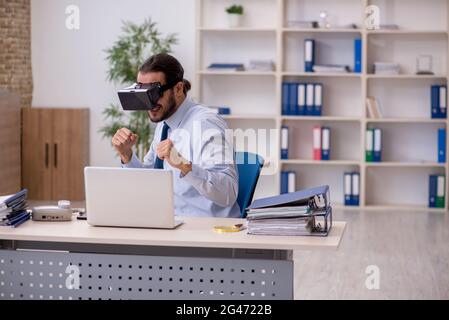 Un jeune employé porte des lunettes virtuelles sur son lieu de travail Banque D'Images