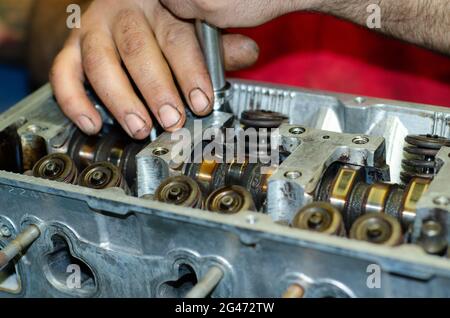 Homme répare démonter la chambre de combustion de la culasse du moteur avec des soupapes encrassées Banque D'Images
