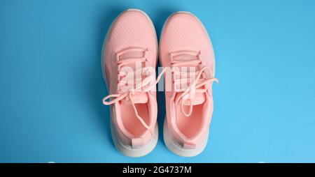 Sneakers roses pour femme avec lacets sur fond bleu, vue du dessus Banque D'Images