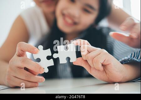 Famille heureuse, fille asiatique jouant puzzle puzzle avec sa mère pour le concept de famille, femme adulte enseigne l'enfant à résoudre des puzzles, , succès et strat Banque D'Images