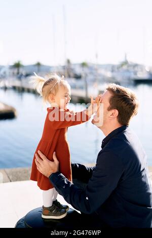 La petite fille joue Peek-a-boo avec son papa sur un port de plaisance Banque D'Images