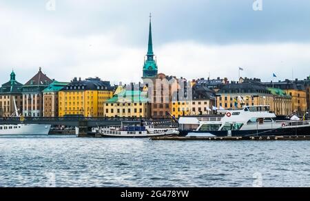 Vue panoramique depuis le bateau sur les maisons en bord de mer à Gamla Stan, les bateaux touristiques et Skeppsholmsbron (pont de Skeppsholm) avec l'or Banque D'Images