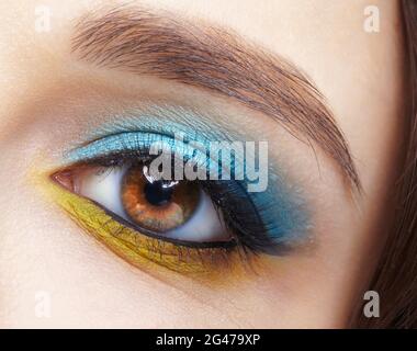 Œil de femme humain avec ombres à paupières bleu fumé et doublure jaune. Banque D'Images