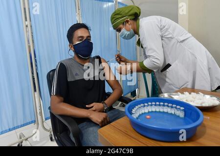 Dhaka. 19 juin 2021. Un travailleur médical inocule un homme avec une dose du vaccin chinois Sinopharm COVID-19 à Dhaka, au Bangladesh, le 19 juin 2021. Le Bangladesh a repris samedi l'administration de la première dose du vaccin COVID-19 dans certaines parties du pays grâce aux vaccins Sinopharm donnés par la Chine. Credit: Xinhua/Alay Live News Banque D'Images