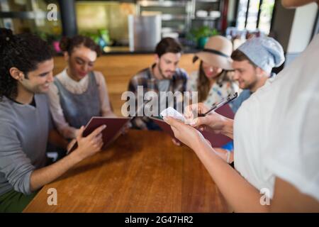 Serveuse prenant les commandes des clients au restaurant Banque D'Images