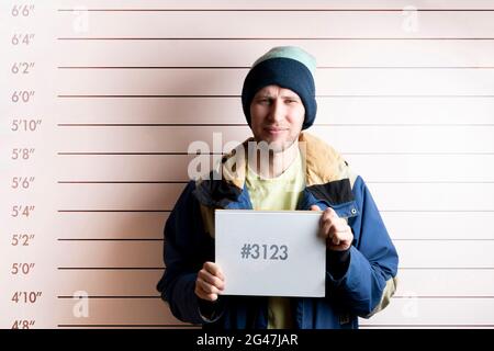 un jeune homme prisonnier arrêté tenant une carte placée devant le tableau de hauteur Banque D'Images