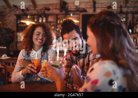 Jeunes amis en interaction les uns avec les autres d'avoir des boissons Banque D'Images
