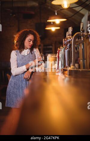 Femme sérieuse ayant le vin rouge au comptoir Banque D'Images