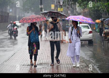 Dhaka, Bangladesh. 19 juin 2021. Les gens se cachent de la pluie sous des parasols pendant une pluie sur la rue Farmgate. La forte baisse de la mousson a causé une exploitation forestière extrême dans la plupart des régions de la ville de Dhaka, au Bangladesh. Les routes ont été submergées, ce qui a rendu les déplacements lents et dangereux. Crédit : SOPA Images Limited/Alamy Live News Banque D'Images