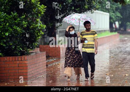 Dhaka, Bangladesh. 19 juin 2021. Un couple se cache de la pluie sous un parapluie sur l'avenue Manik mia à Dhaka. La forte baisse de la mousson a causé une exploitation forestière extrême dans la plupart des régions de la ville de Dhaka, au Bangladesh. Les routes ont été submergées, ce qui a rendu les déplacements lents et dangereux. Crédit : SOPA Images Limited/Alamy Live News Banque D'Images