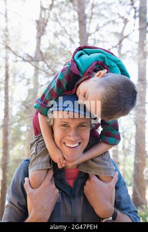 Portrait of happy father carrying son on shoulders Banque D'Images