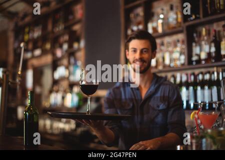 Portrait d'un barman tenant un plateau avec un verre de vin rouge Banque D'Images